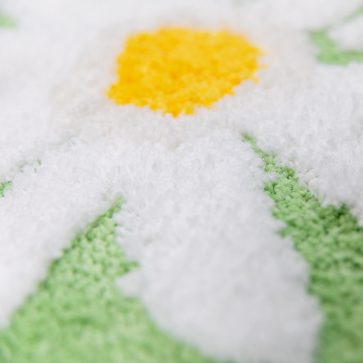 Close-up of a cross-stitched snowman with a yellow carrot nose on a white background.