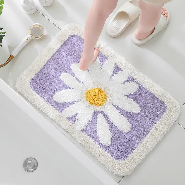 Floral-patterned bath mat with a daisy design on a bathroom floor.