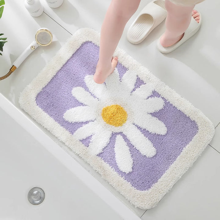 Floral-patterned bath mat with a daisy design on a bathroom floor.