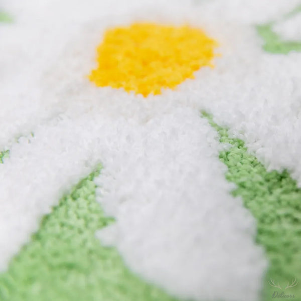 Close-up of a cross-stitched snowman with a yellow carrot nose on a white background.