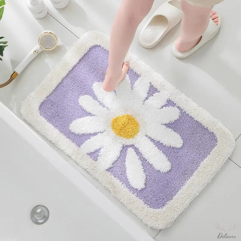 Floral-patterned bath mat with a daisy design on a bathroom floor.