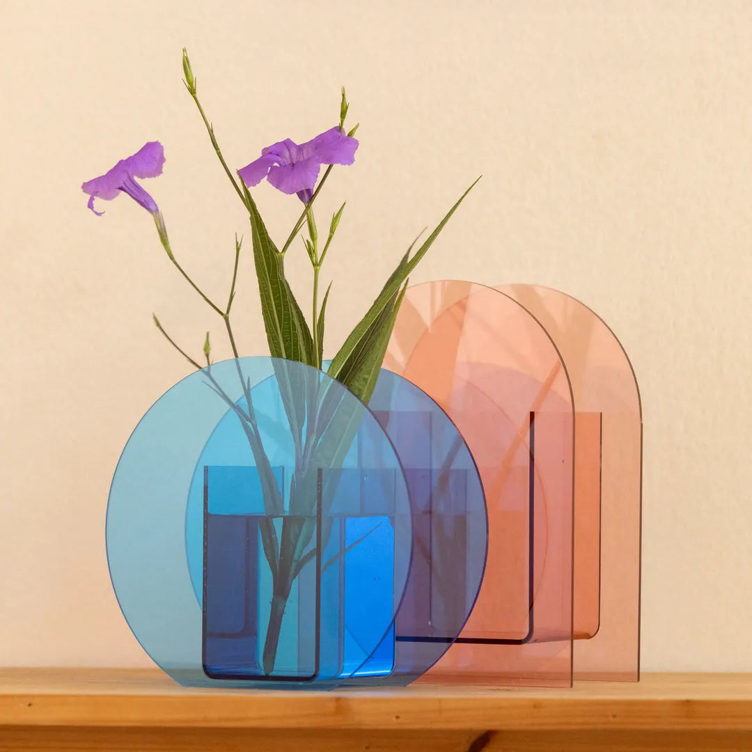 Two translucent acrylic vases, one blue and one peach-pink