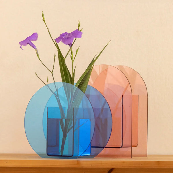 Two translucent acrylic vases, one blue and one peach-pink