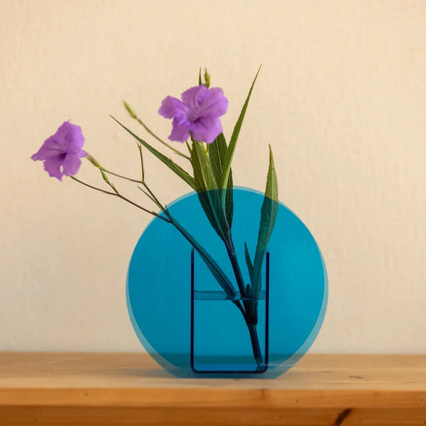 A translucent blue circular vase with a rectangular base