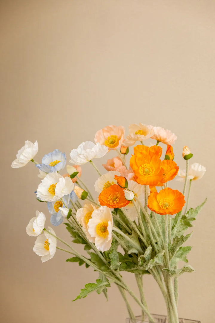 A bouquet of artificial flowers in a clear glass vase