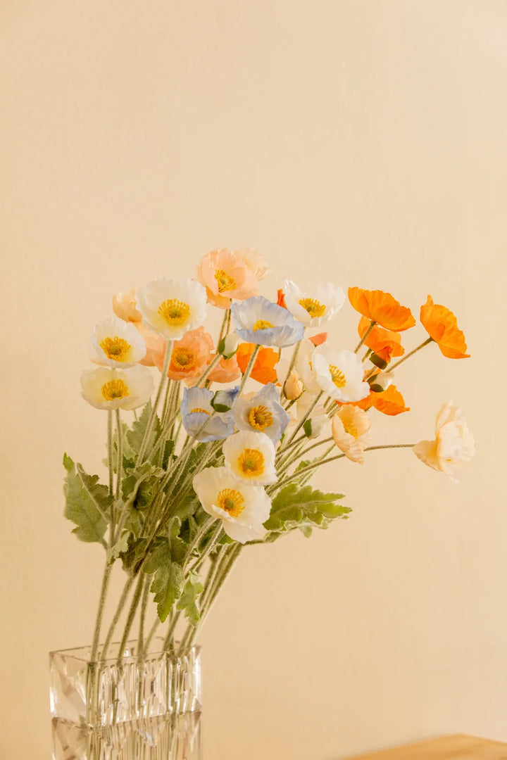 A bouquet of artificial flowers in white, peach, orange, and light blue 